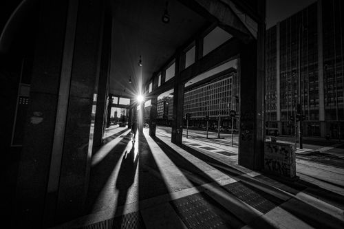 Free Black and white of anonymous silhouette of person walking along open passage of building Stock Photo