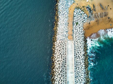 Stunning aerial view of a coastal jetty in Abidjan, Côte d'Ivoire with surrounding sea and sand.