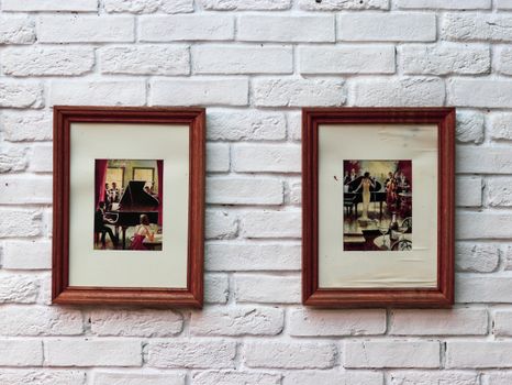 Two framed artworks on a textured white brick wall, creating a nostalgic aesthetic.