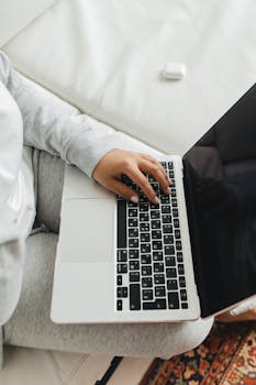 Close-up of a person typing on a laptop while sitting comfortably indoors.