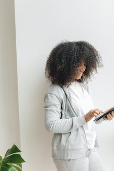 African American woman smiling and using tablet with a sleek, minimalist background.