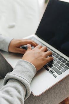 Close-up of hands typing on a laptop, showcasing technology and connectivity.