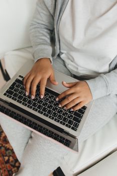 Close-up of hands typing on a laptop, wearing casual clothing, working from home.