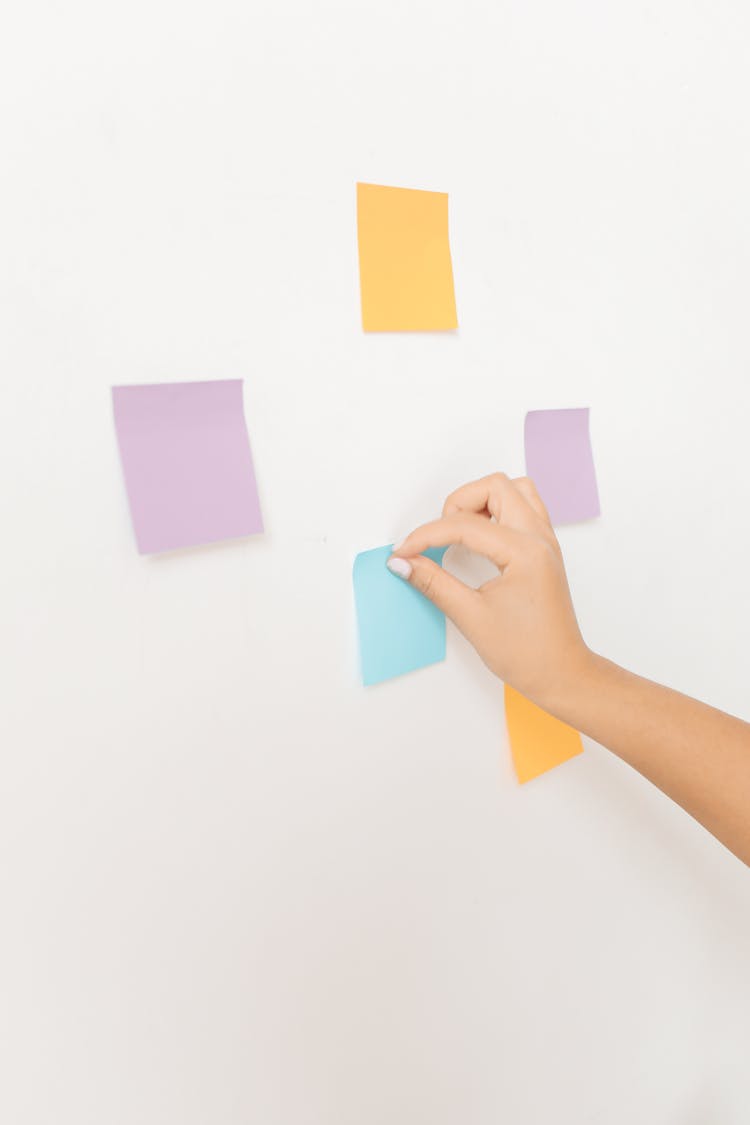 A Person Posting Sticky Notes On A White Wall