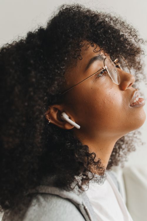 Free Close-up of a black woman with earphones in a relaxed, thoughtful pose. Stock Photo