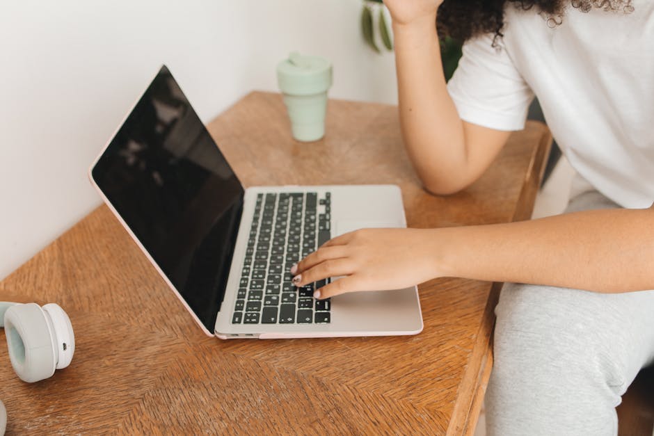 Como Criar um Espaço de Trabalho Aconchegante e Produtivo 2 Focused woman working remotely from home with a laptop on a wooden desk.