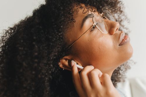 Free Close-up of a woman wearing eyeglasses and earphones, enjoying music. Stock Photo