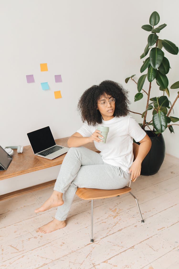 A Woman Sitting On A Chair And Holding A Tumbler