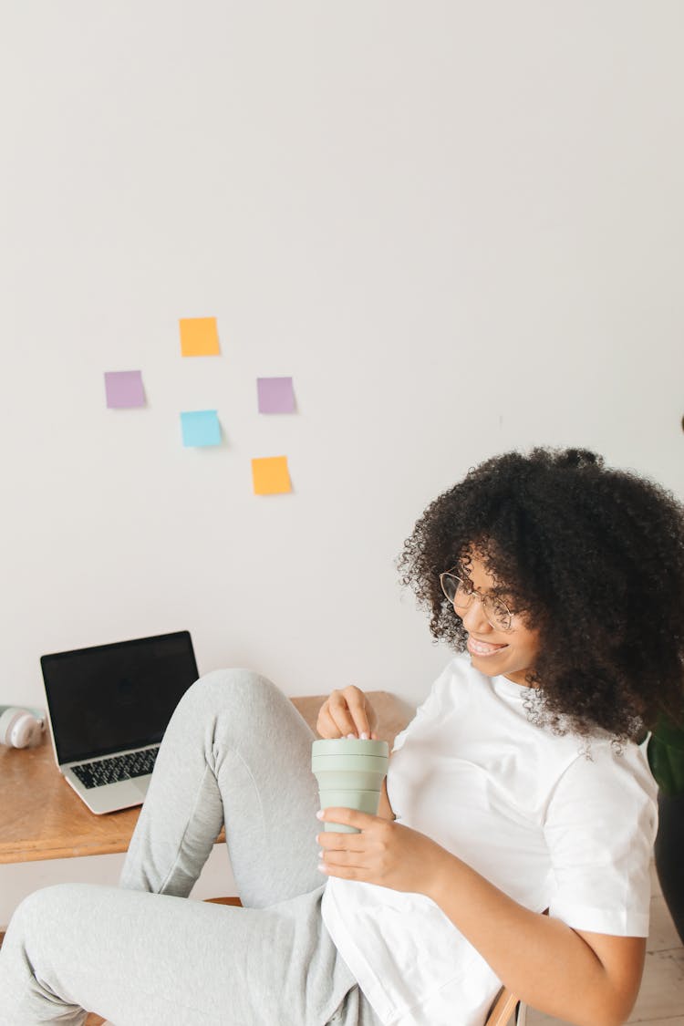 A Woman Sitting On A Chair And Holding A Tumbler 