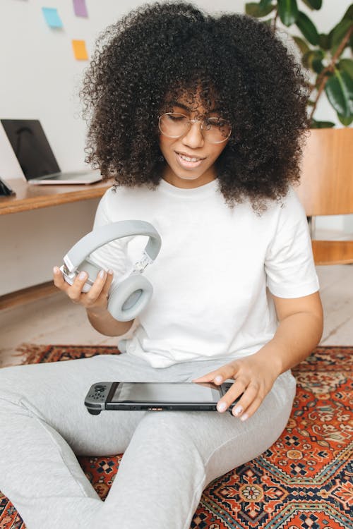 A Woman Holding a Headphone and a Video Game Console