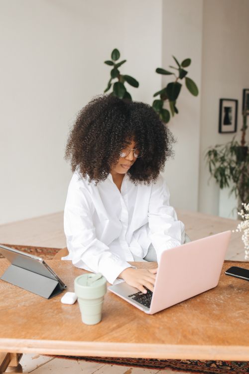 Free Young black woman with afro hair working on laptop in cozy home office setting. Stock Photo