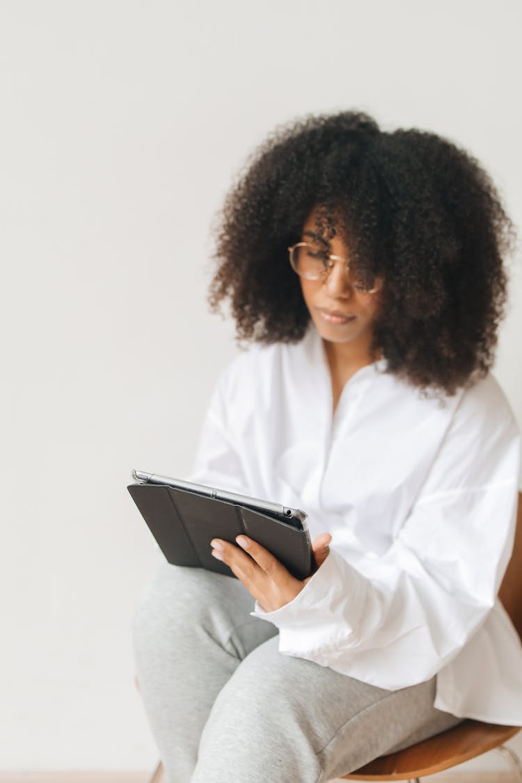 Person Sitting On Chair While Holding A Tablet