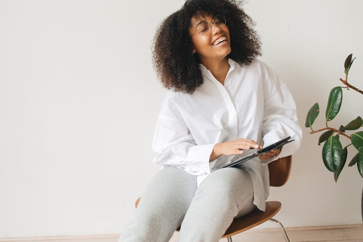 Woman Laughing While Holding A Tablet