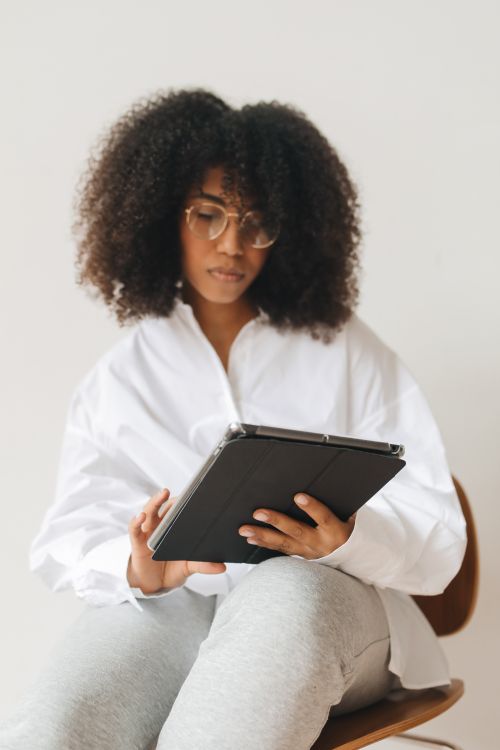 Free Young woman with curly hair using a tablet for remote work at home. Stock Photo