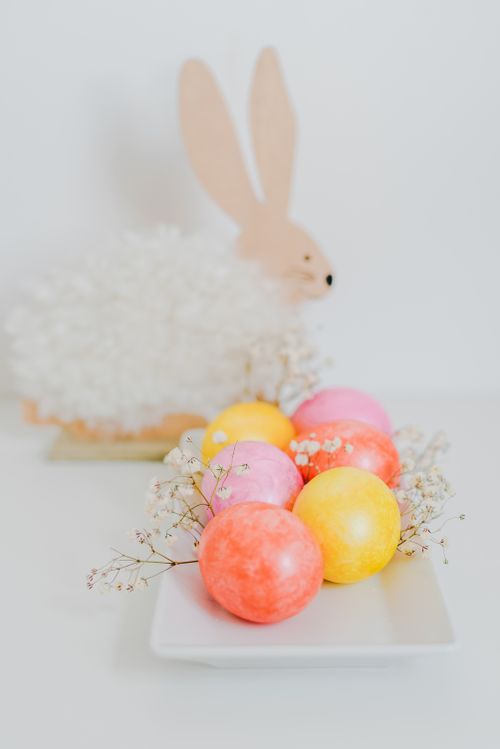 Free Vibrant Easter eggs on a white plate, decorated with a fluffy bunny in a bright setting. Stock Photo