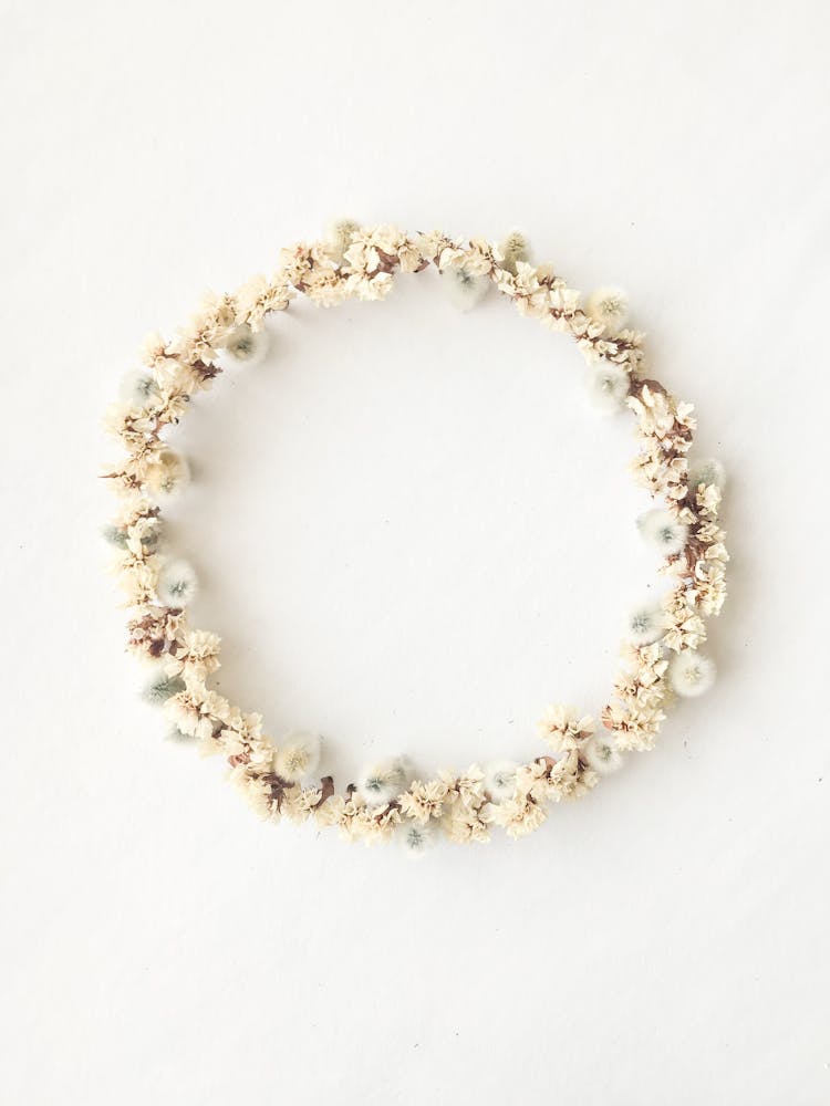 Wreath With Dandelions And White Blossoms On Table