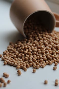 Close-up of spilled chickpeas from a cup, showcasing their texture and nutritious quality.