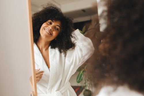 Free Happy woman with curly hair smiling in a bathrobe at home. Stock Photo