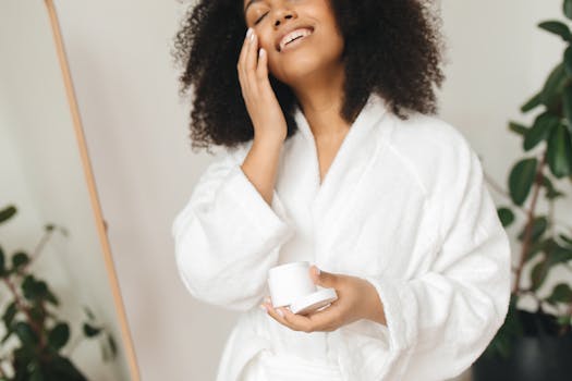 A woman in a bathrobe applies cream as part of her self-care routine indoors.