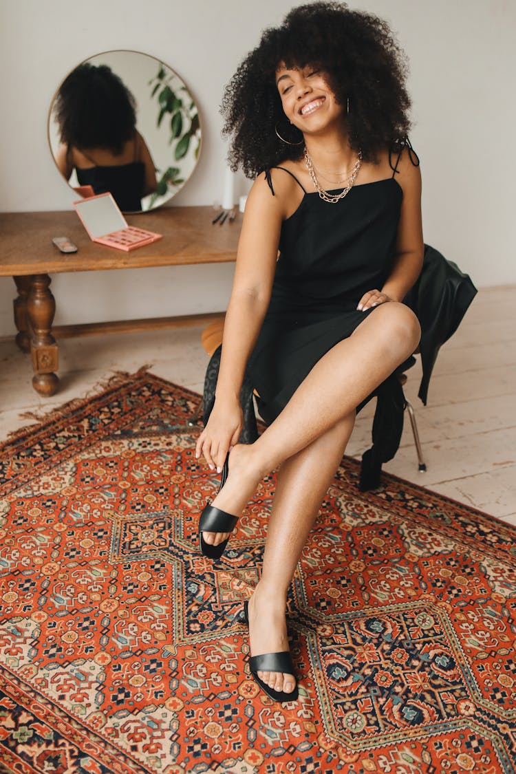 Woman In Black Sleeveless Dress Sitting On Red And White Persian Rug