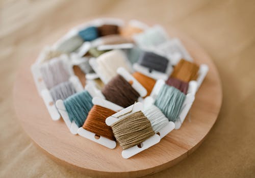 Free Colorful Embroidery Threads on a Round Wooden Tray Stock Photo