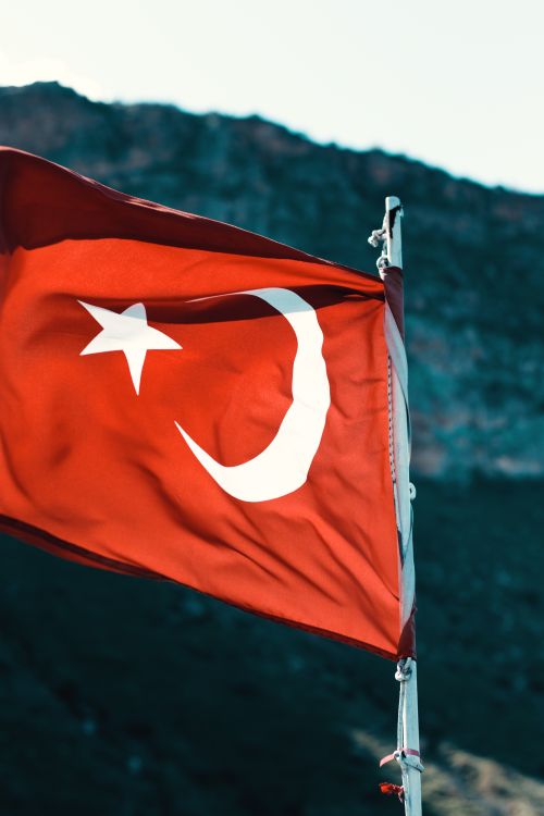 Free A vibrant Turkish flag waving against a mountainous backdrop, symbolizing patriotism. Stock Photo