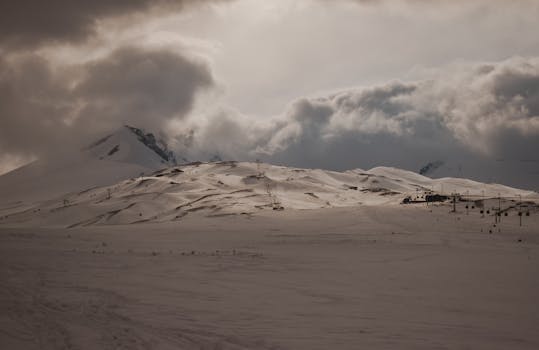 A breathtaking view of snow-covered mountains under dramatic clouds, captured in winter.