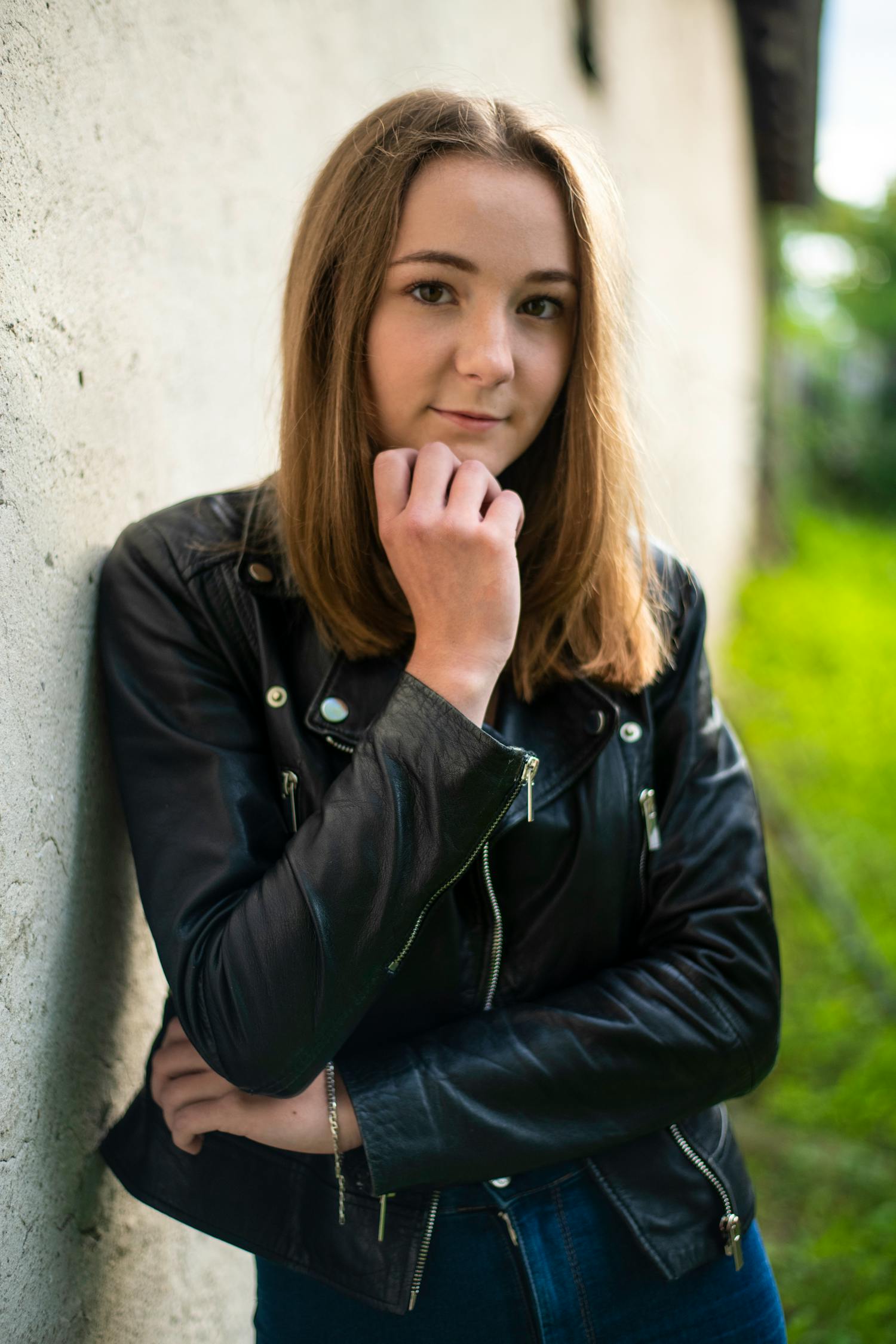 A Beautiful Lady in a Leather Jacket Leaning on a Wall · Free Stock Photo
