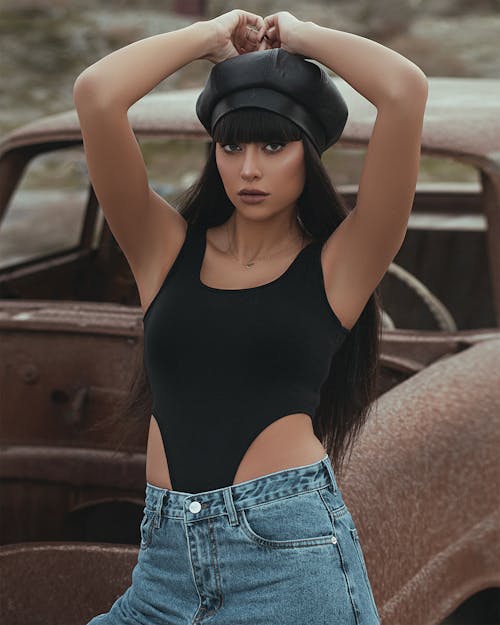 Woman in Black Tank Top and Blue Denim Shorts Wearing Black Cap