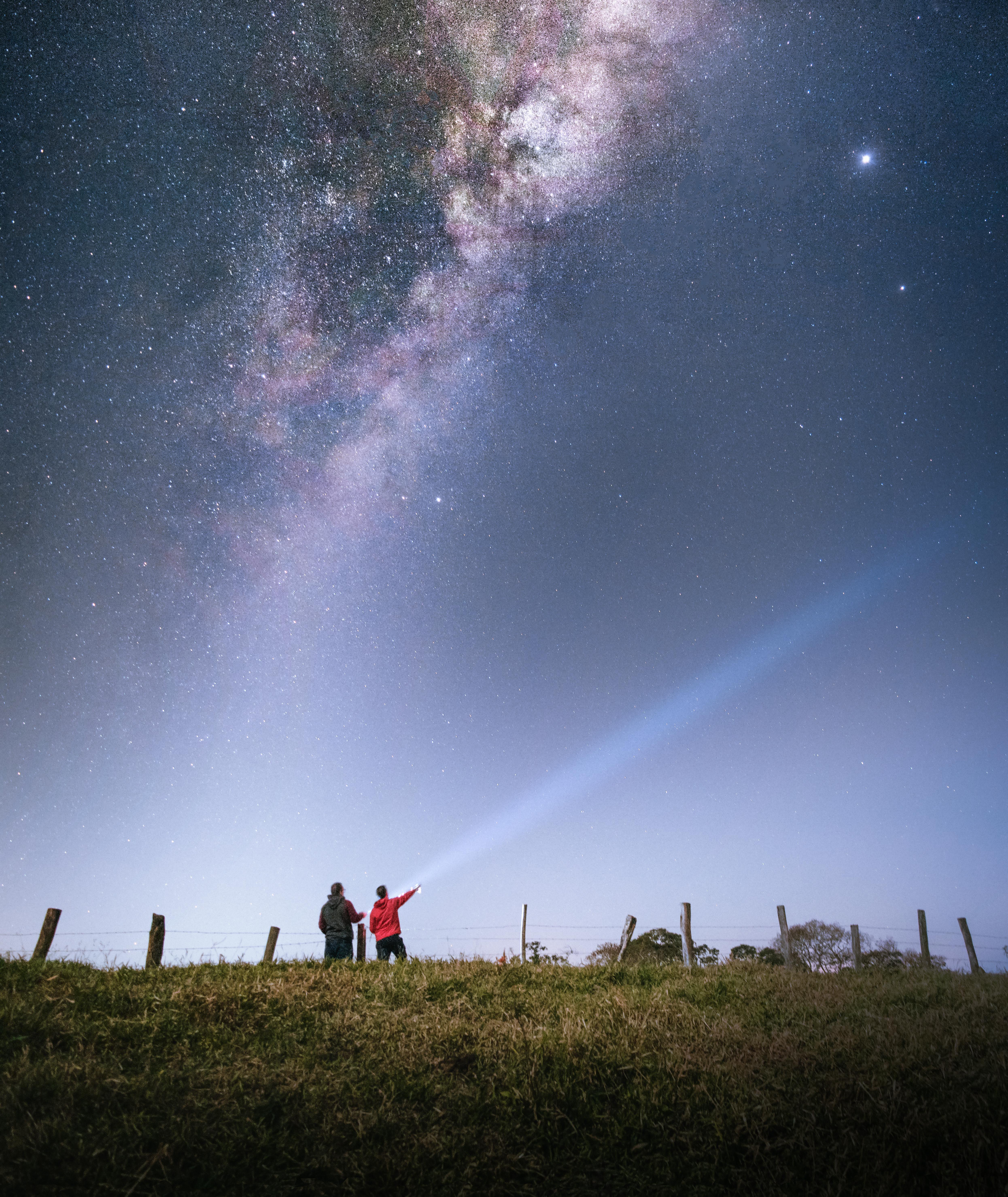 Two people stargazing under a vibrant Milky Way sky in Estiva, Brazil.
