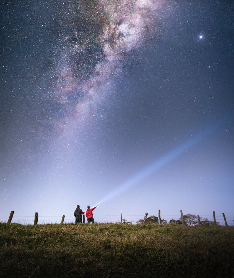 People Shining Out A Flashlight Under A Starry Sky