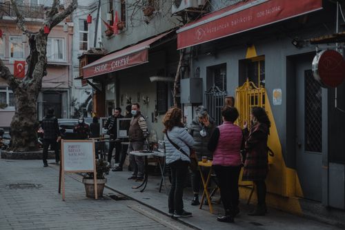 Free People in winter clothing gather outside cafes in Istanbul's Kuzguncuk district, highlighting urban culture. Stock Photo