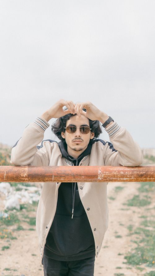 Free Stylish man with sunglasses leaning on a rustic barrier in Morocco. Stock Photo