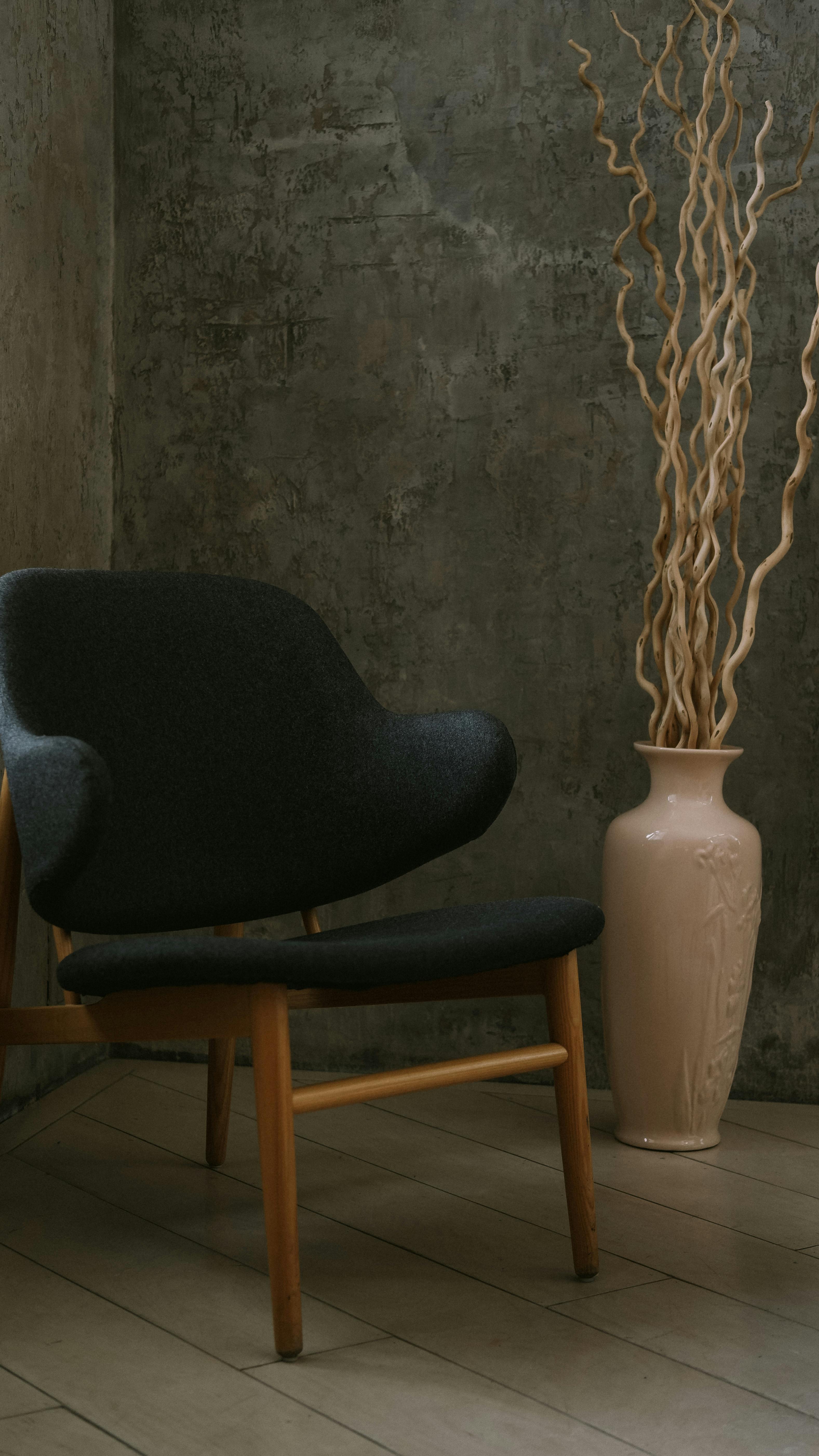 Free A mid-century modern chair beside a decorative vase in a minimalistic indoor setting. Stock Photo