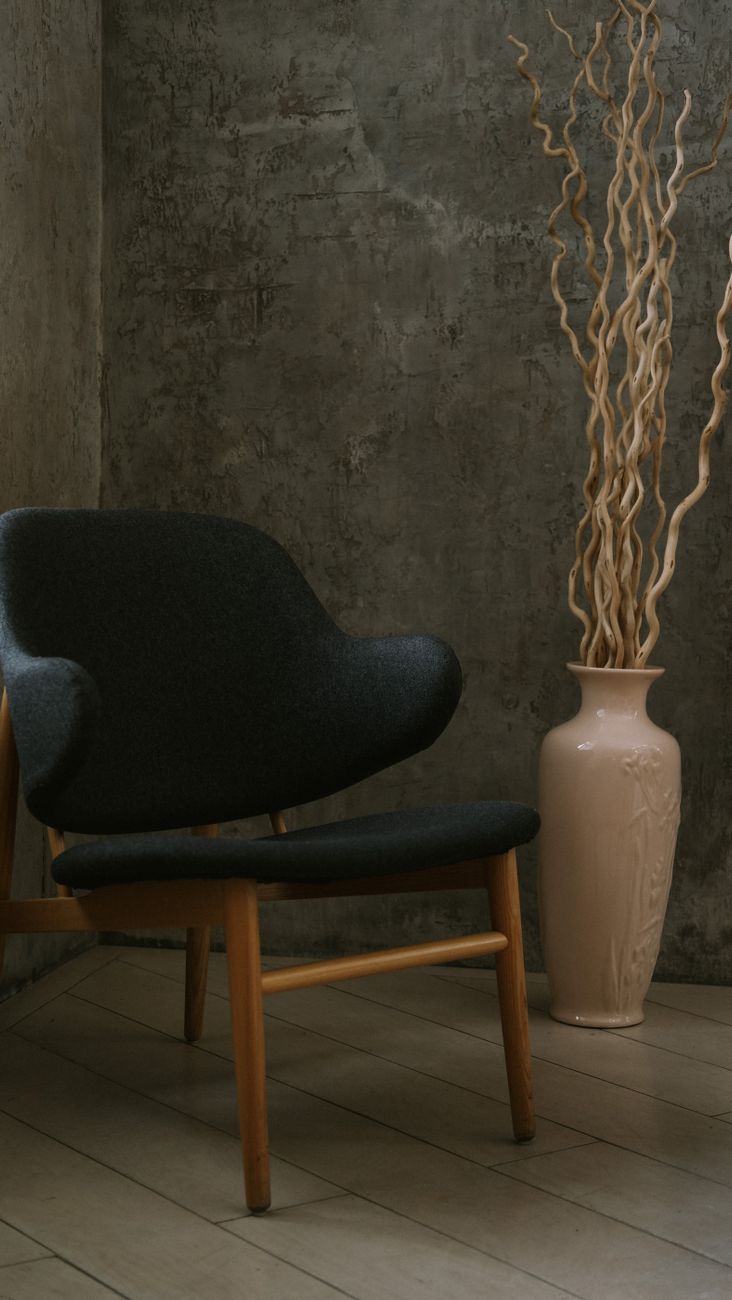 A mid-century modern chair beside a decorative vase in a minimalistic indoor setting.. century, modern, chair