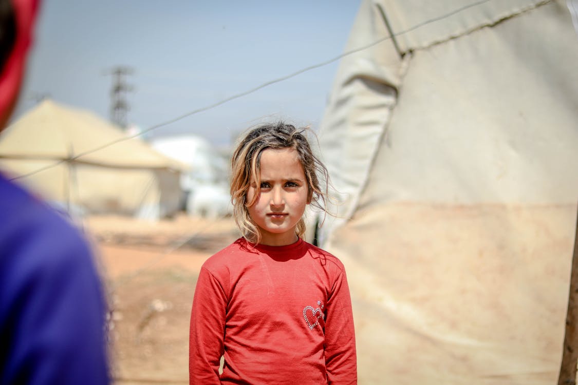 A Girl in Red Long Sleeves at a Refugee Camp