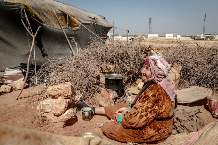 An Elderly Woman Cooking At A Refugee Camp