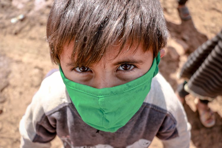 A Young Boy Wearing A Green Face Mask