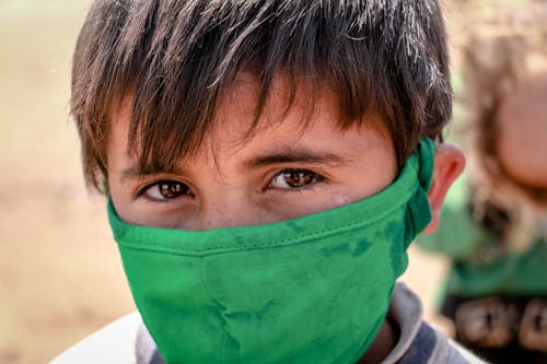 A Young Boy Wearing a Green Face Mask