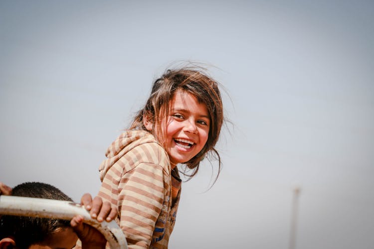 A Young Girl Refugee With A Cheerful Smile