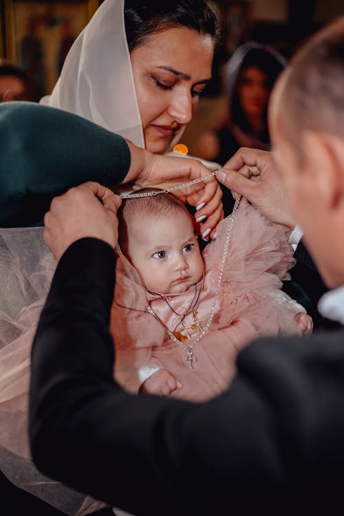 Free High angle of godparents christening little infant girl in dress in Christian church Stock Photo