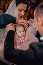 High angle of godparents christening little infant girl in dress in Christian church
