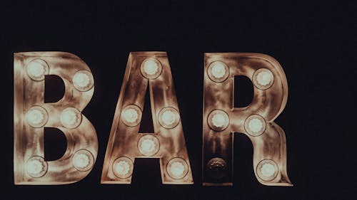 Bright lights of shimmering word bar on black background at late dark night