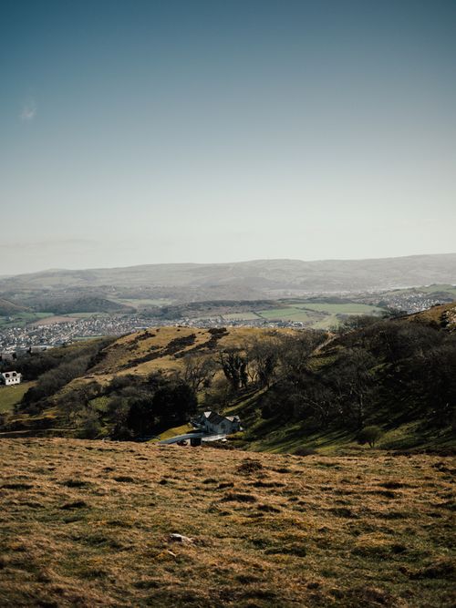 Free Picturesque landscape of rolling hills in Wales with distant town view. Stock Photo
