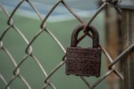 A Rusty Padlock on a Chain-Link Fence