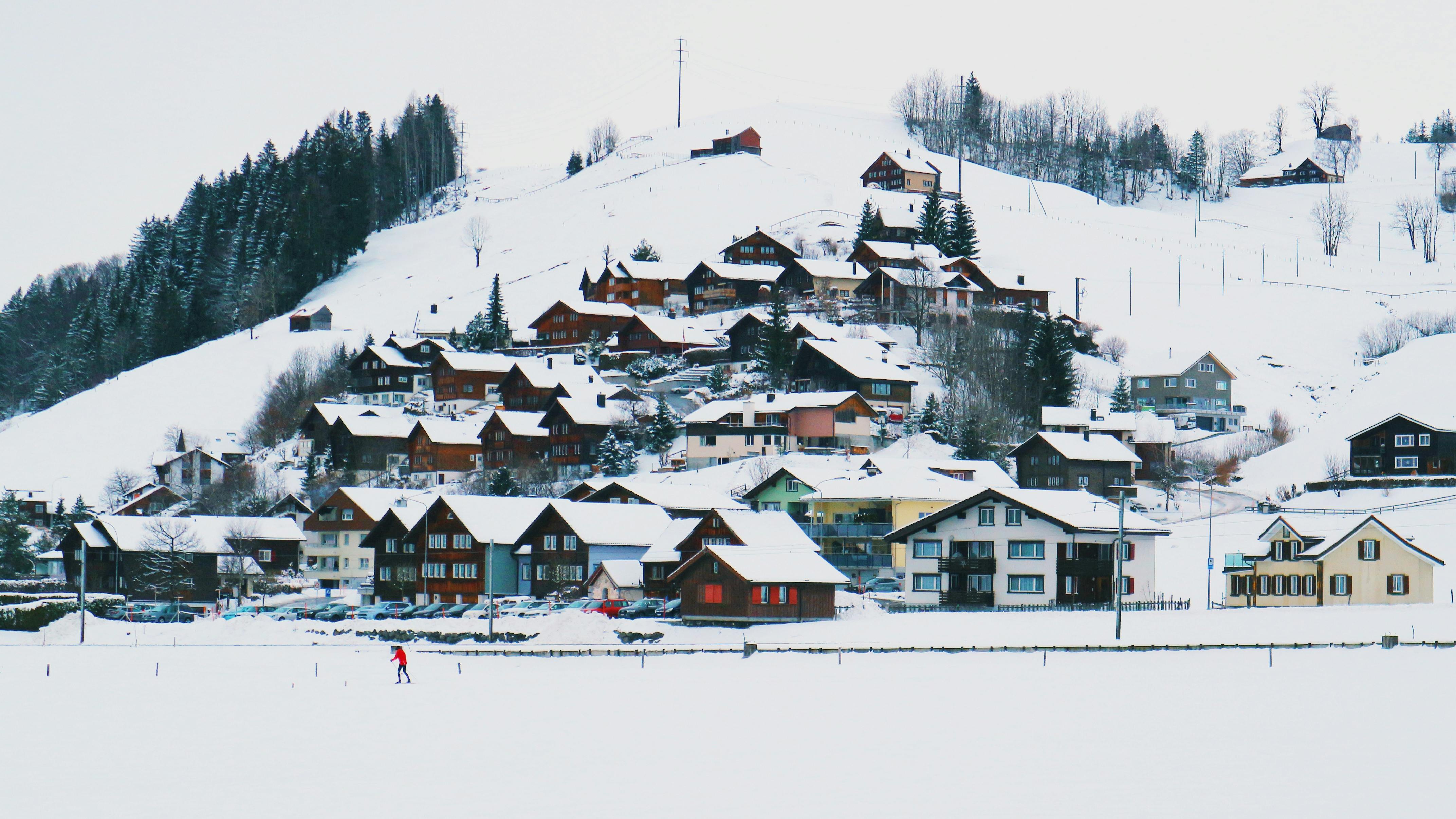 Prescription Goggle Inserts - Idyllic snow-covered village nestled in winter landscape with skier in red jacket enjoying the scenery.