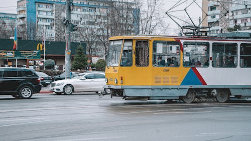 People Riding a Yellow Tram on the Road