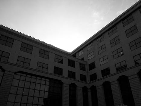 Black and white image of modern building facade with glass windows and concrete walls.