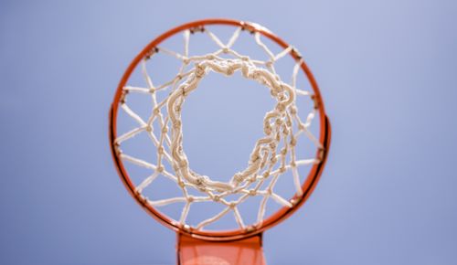 Free From below of metal basketball hoop with net hanging on sports ground against blue sky Stock Photo