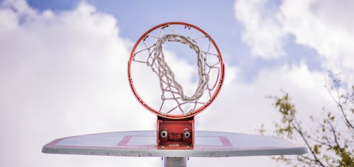 Free Low angle of modern basketball hoop on backboard against cloudy sky on sports ground Stock Photo